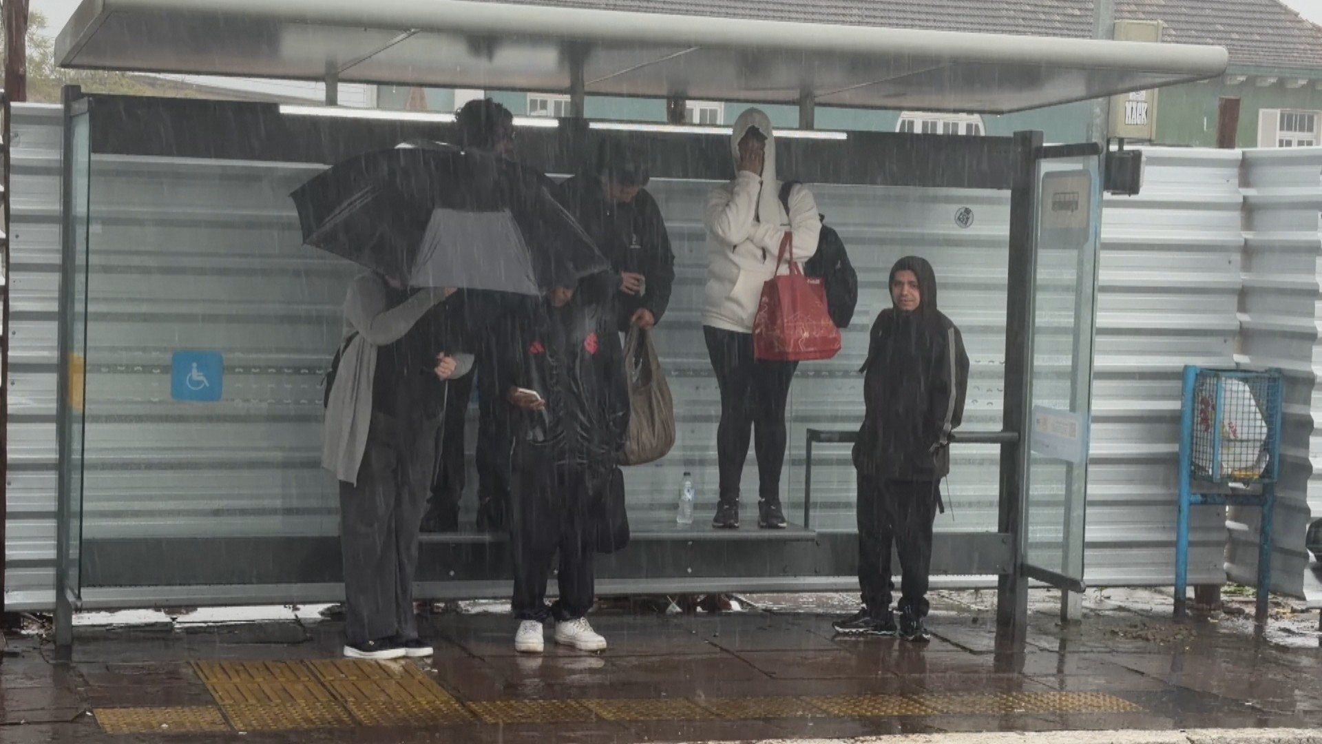 FOTO: passageiros sobem em banco para se proteger de chuvarada em parada de ônibus de Porto Alegre